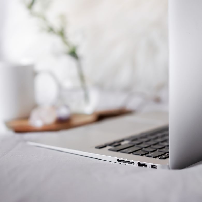 3 Smart Ways To Make Money With A New Blog: Start Monetizing In Year One 5 Sell services to make money with a new blog - laptop on a bed.