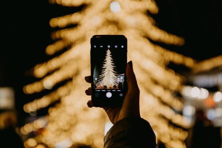 Taking a photo of a lit Christmas tree - Christmas Hashtags for Instagram