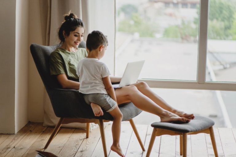 A mom sitting in a chair, using a laptop with her child looking on - balancer being a mom with blogging.