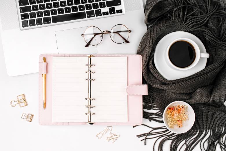 Desktop with pink planner and cup of coffee on a black scarf - 7 mistakes bloggers make. 