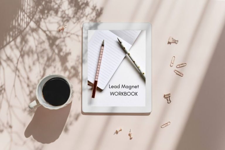 An iPad with an image of pens and a notebook with "Lead Magnet Workbook" written on it and a cup of coffee and pins on a beige table - freebies for newsletters and lead magnet ideas for blogs.