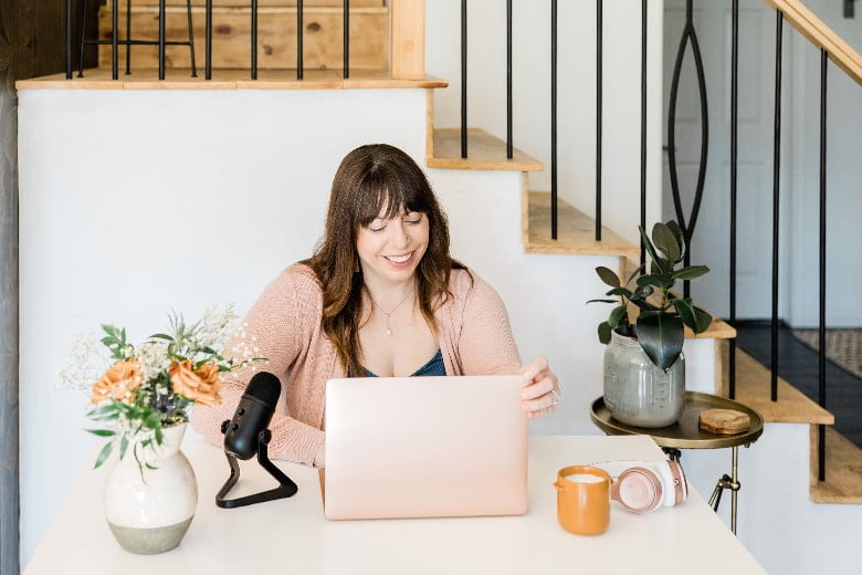 A woman sitting at a desk in her home office, looking at your laptop - best stock photo sites for bloggers.