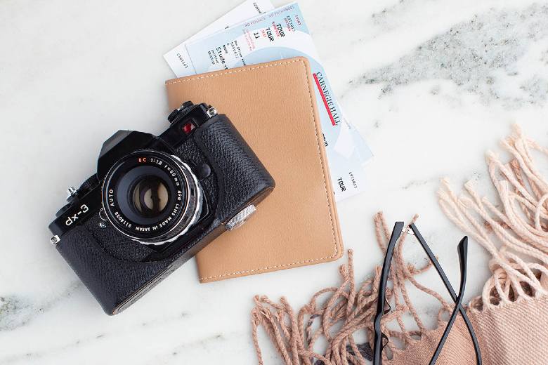 Camera with a tan leather protector for tickets inside - travel hashtags for Instagram.