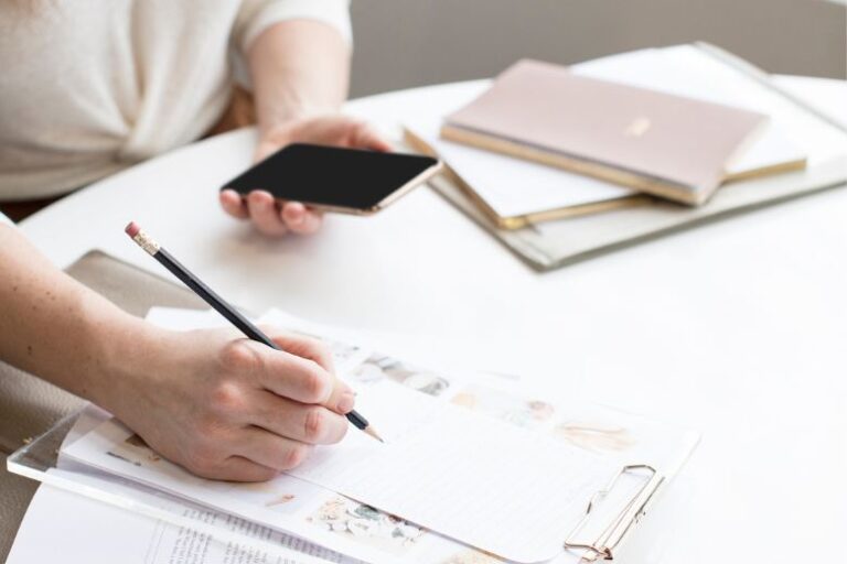 Woman writing down notes - how to set blog goals.