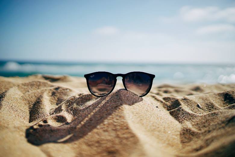 Sunglasses on a sandy beach - summer wallpapers for iPhone screens.