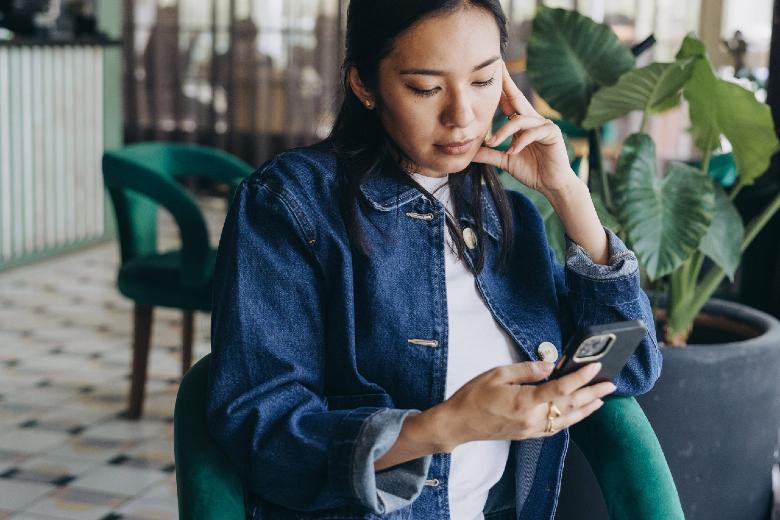 Woman looking at her phone - Facebook group etiquette tips from MargaretBourne.com.