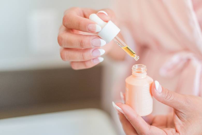 Woman's hands showing trial of a serum using a small bottle and dropper - how to get sponsored posts and brand collaborations. 