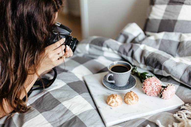 Woman taking photos of food placed on a marble slab on a bed - food photography tips for bloggers.