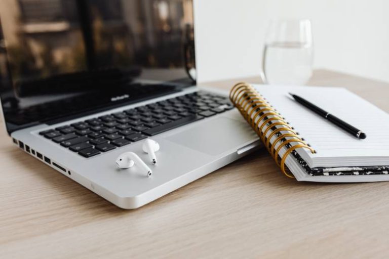 Free WordPress plugins for blogs - laptop on a table with a notebook, pen and earbuds.