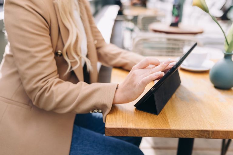 “Starting A Coaching Business” Checklist: 12 Essentials 1 Woman using an iPad - starting an online coaching business checklist from blog coach Margaret Bourne.