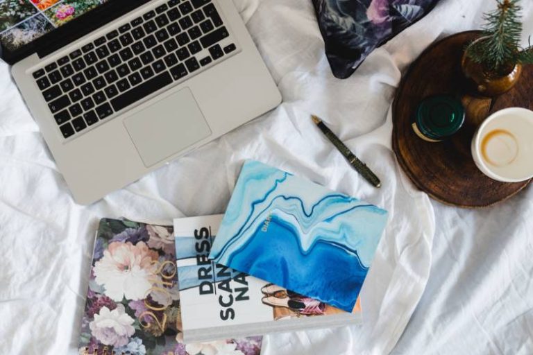 Laptop and notebooks on a bed - how to rebrand your blog.