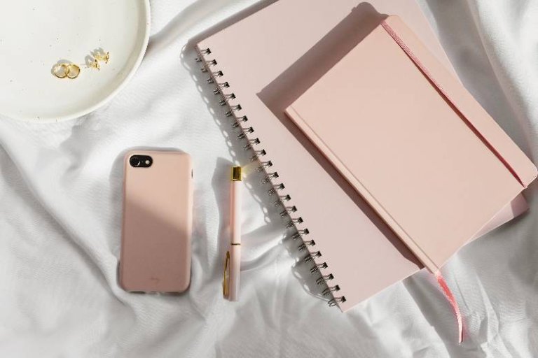 Desktop with blush pink phone and notebooks - best tools for bloggers.