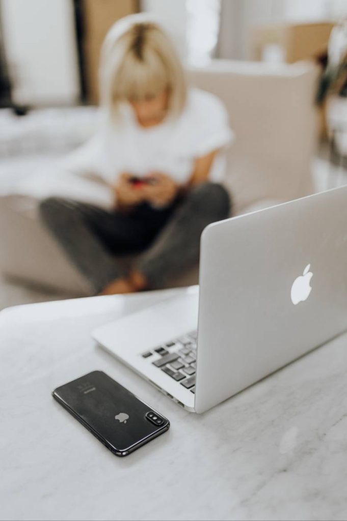 WordPress Setup and Maintenance Guide: What to Do After Installing WordPress 3 Laptop and phone on a desk with a woman in the background - WordPress setup and maintenance.